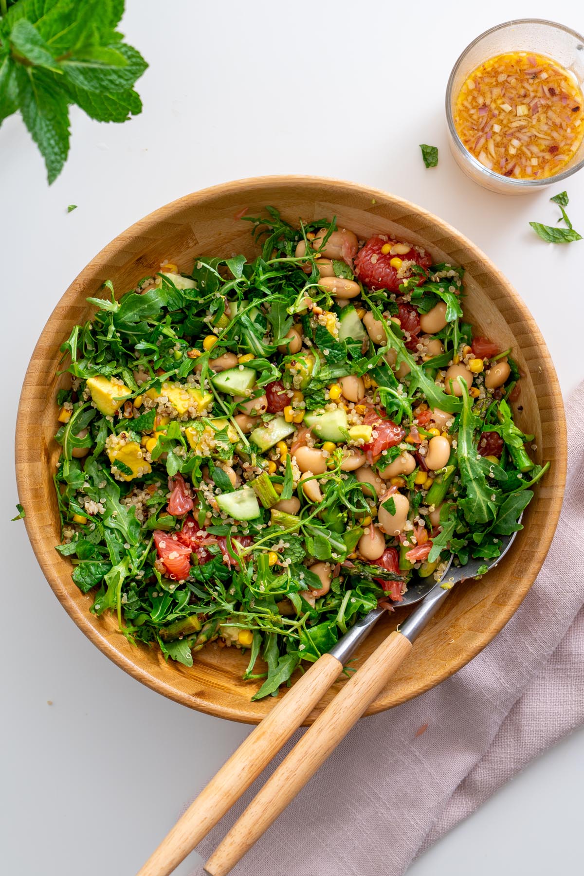 All salad ingredients combined in a wooden bowl with fresh herbs on top