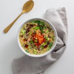 Overhead shot of savory vegan oats topped with kimchi, mushrooms, scallions, and chili oil with a gold spoon on the side