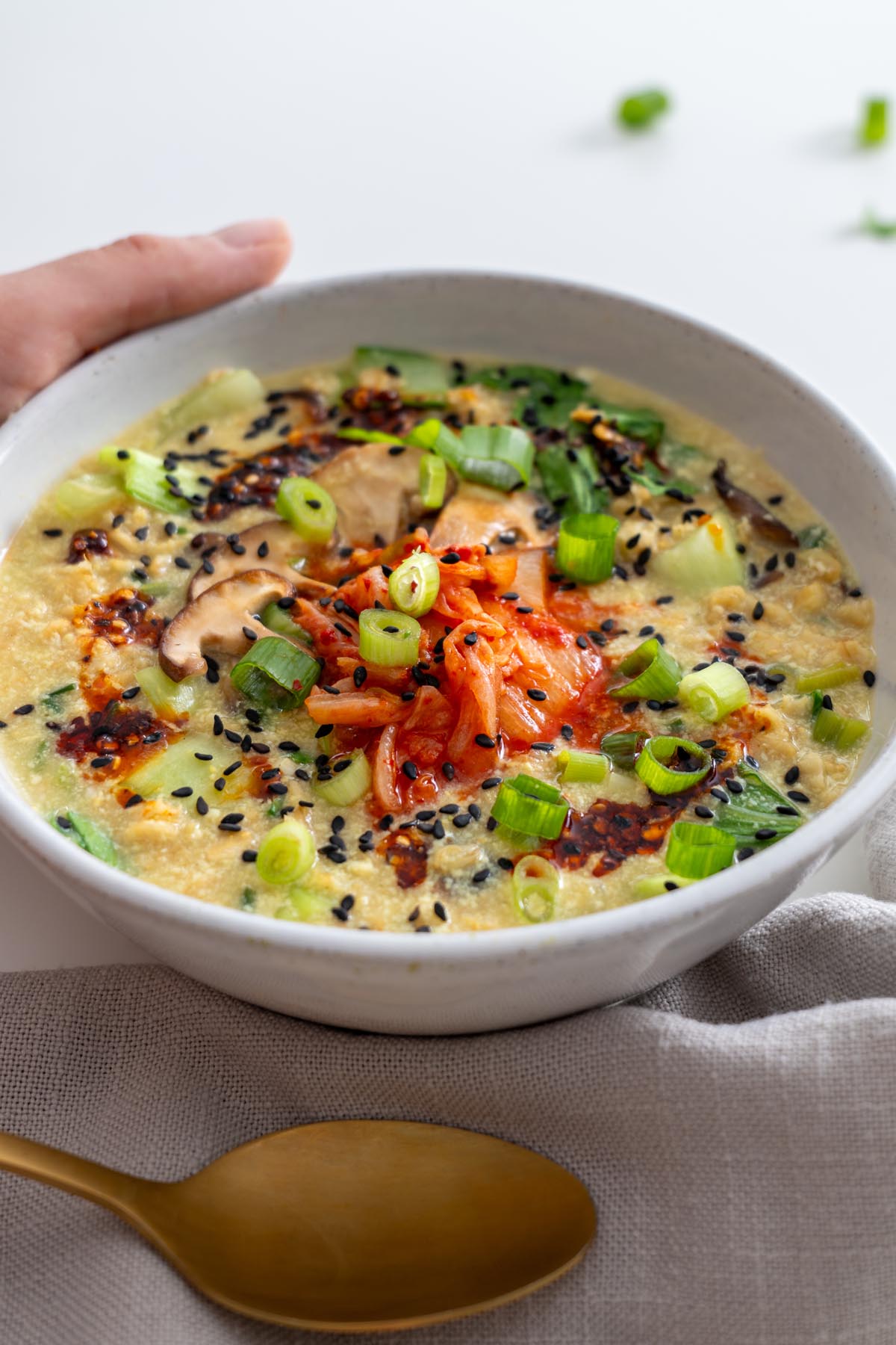 Close-up angle of savory oats with kimchi, mushrooms, scallions, and sesame seeds