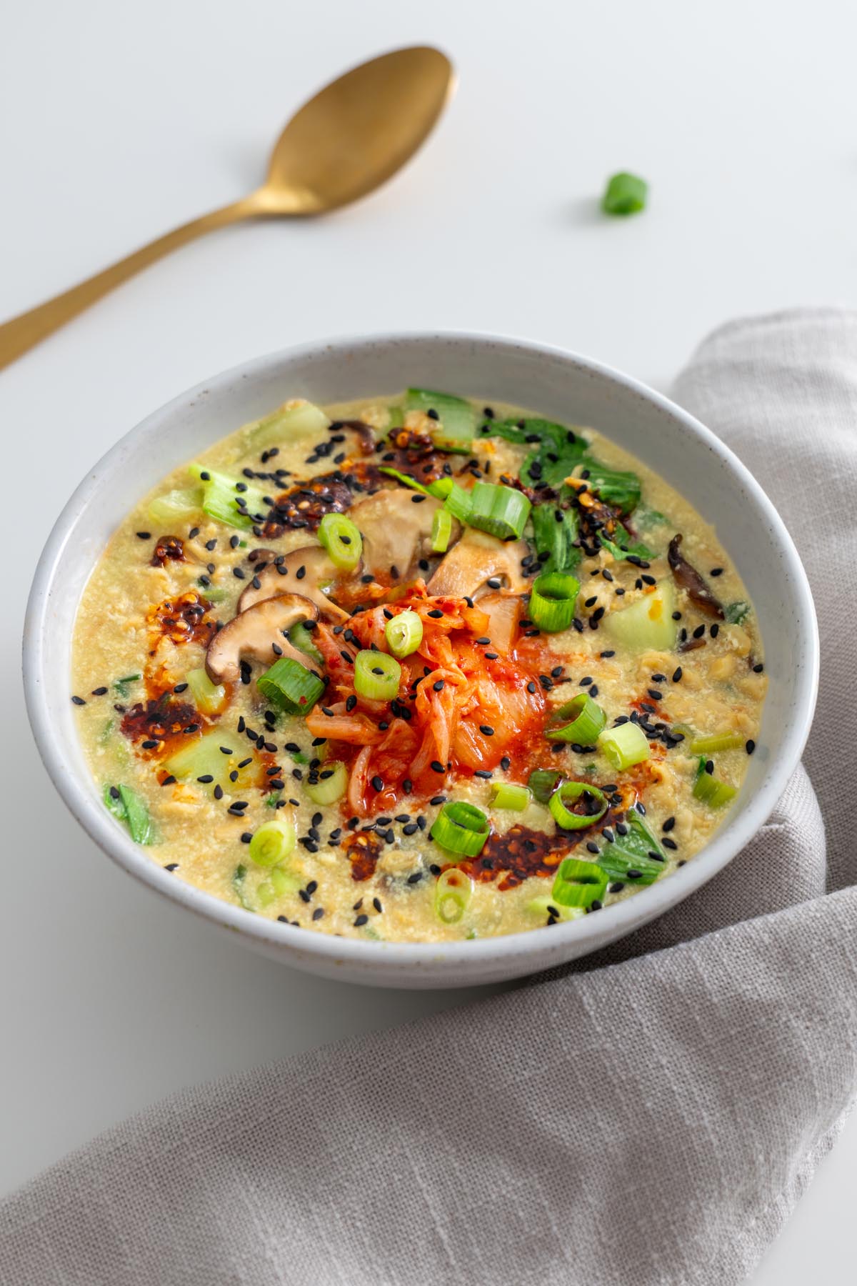 Close-up angle of savory oats with kimchi, mushrooms, scallions, and sesame seeds