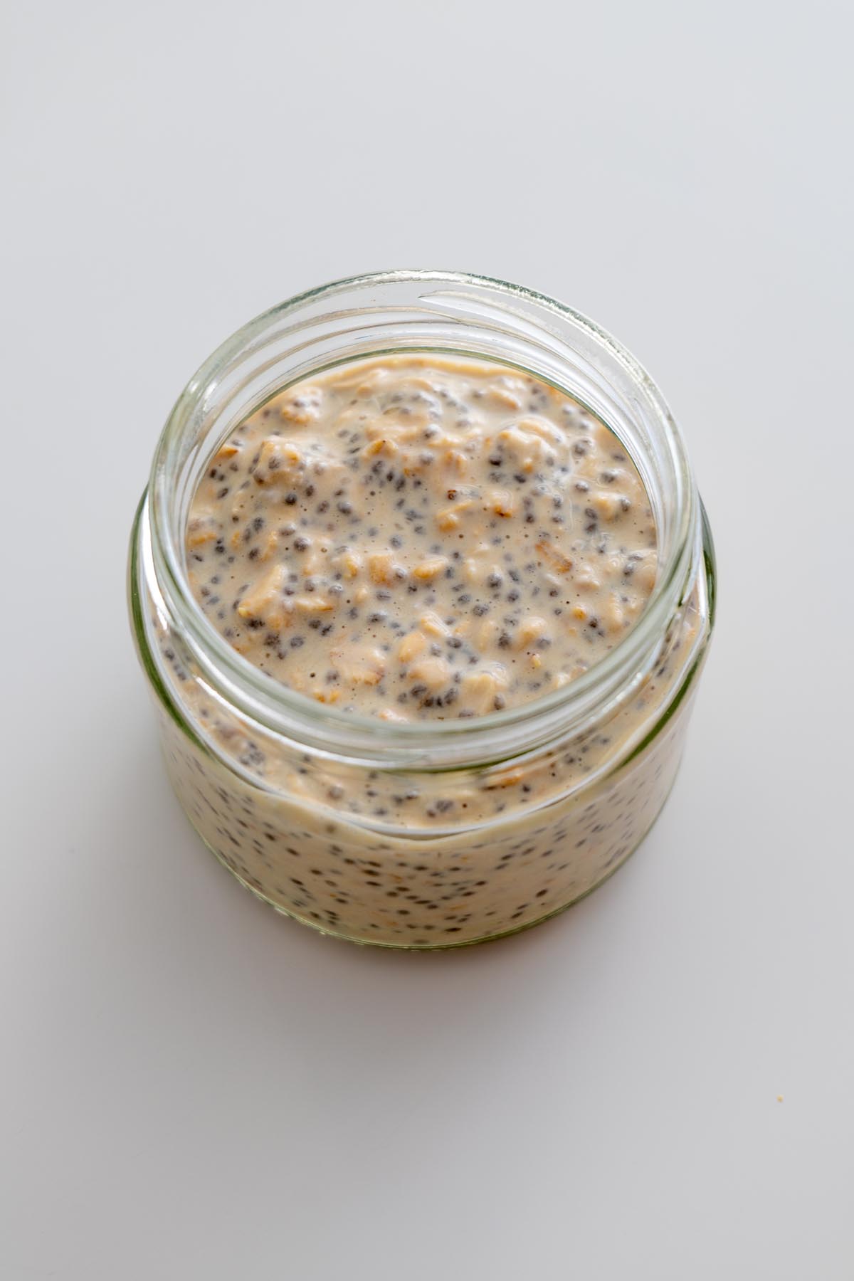 Chilled Snickers overnight oats with visible oats and chia seeds in a glass jar.