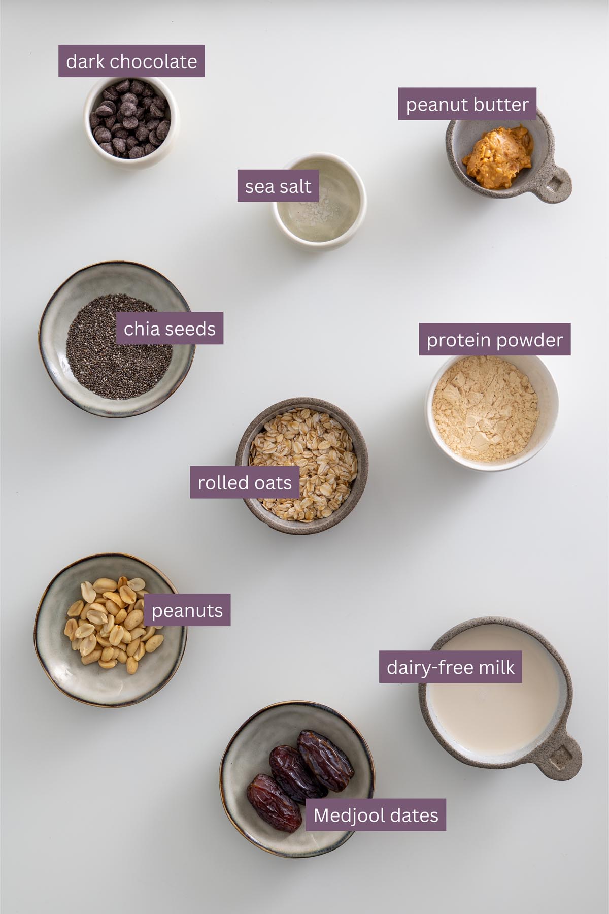 Flat lay of labeled ingredients for Snickers overnight oats including oats, dates, peanut butter, and chocolate.
