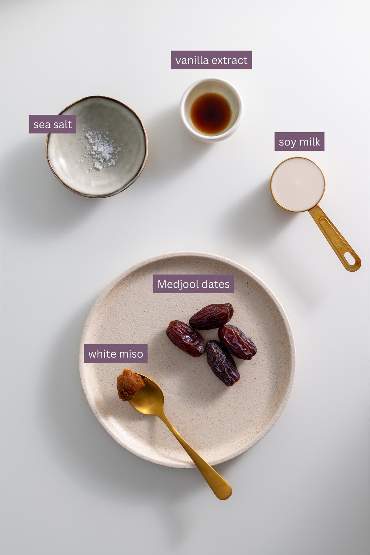 Flat lay of labeled ingredients for the miso caramel including Medjool dates, soy milk, vanilla extract, miso paste, and sea salt.