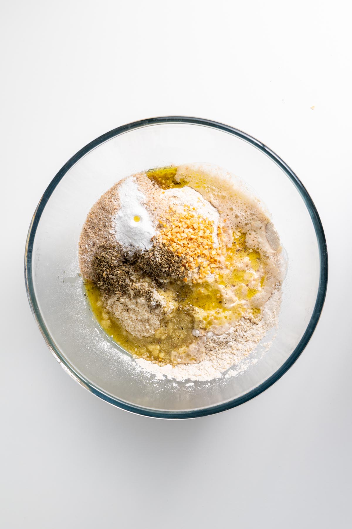Dry and wet ingredients for gluten-free seeded bread in a glass bowl before mixing