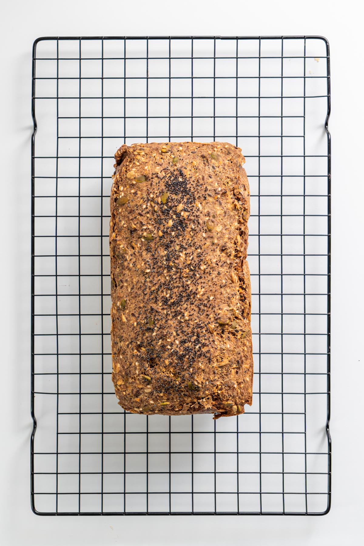 Overhead view of gluten-free seeded bread cooling on a wire rack