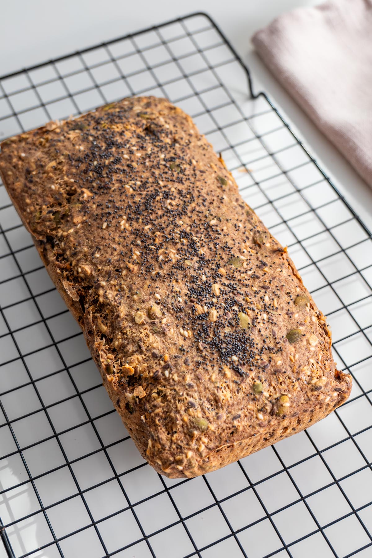 Side angle of gluten-free seeded bread cooling on a rack