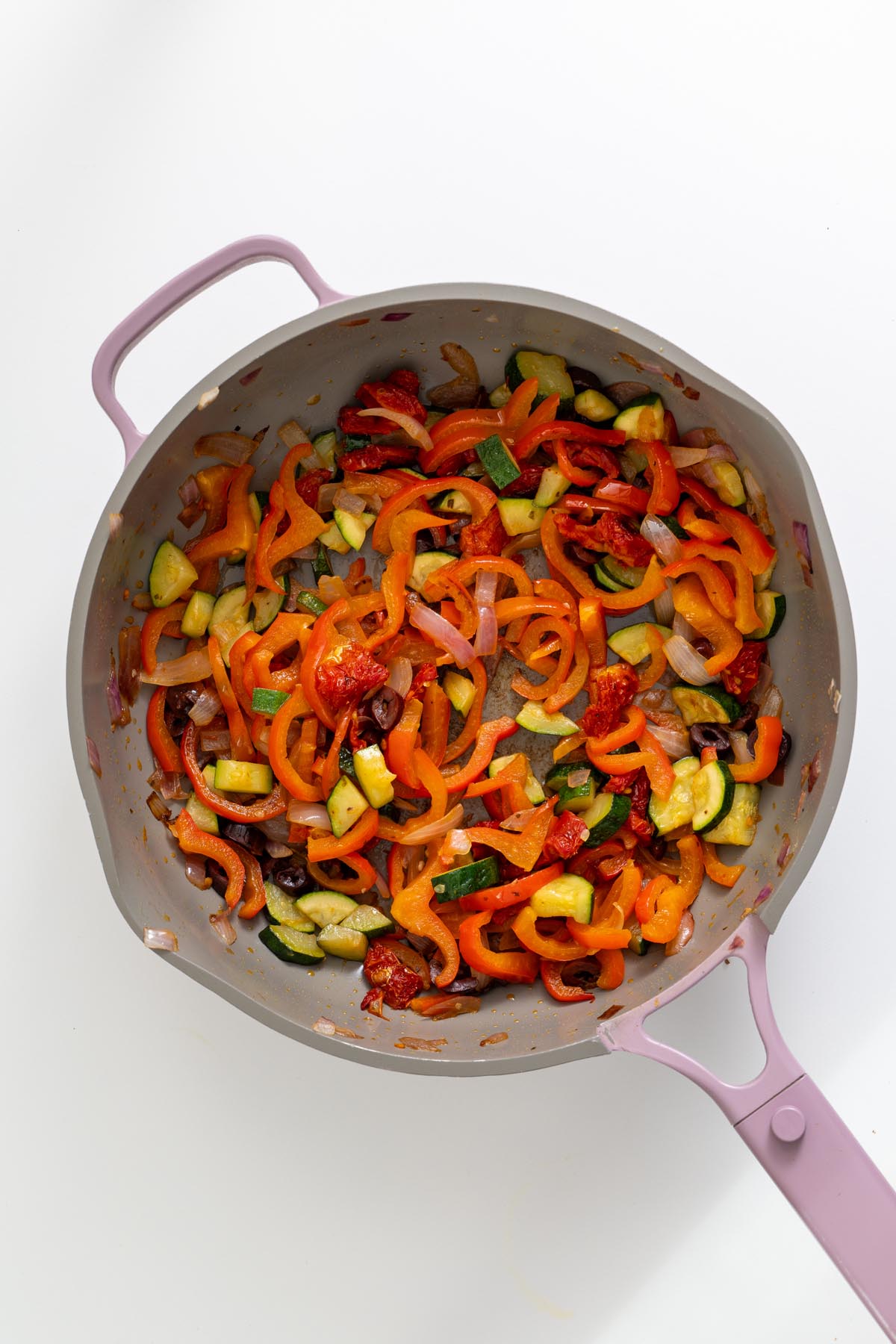 Cooked red onion, zucchini, and bell pepper in a skillet