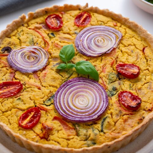Close-up of golden-baked vegan quiche with colorful topping details
