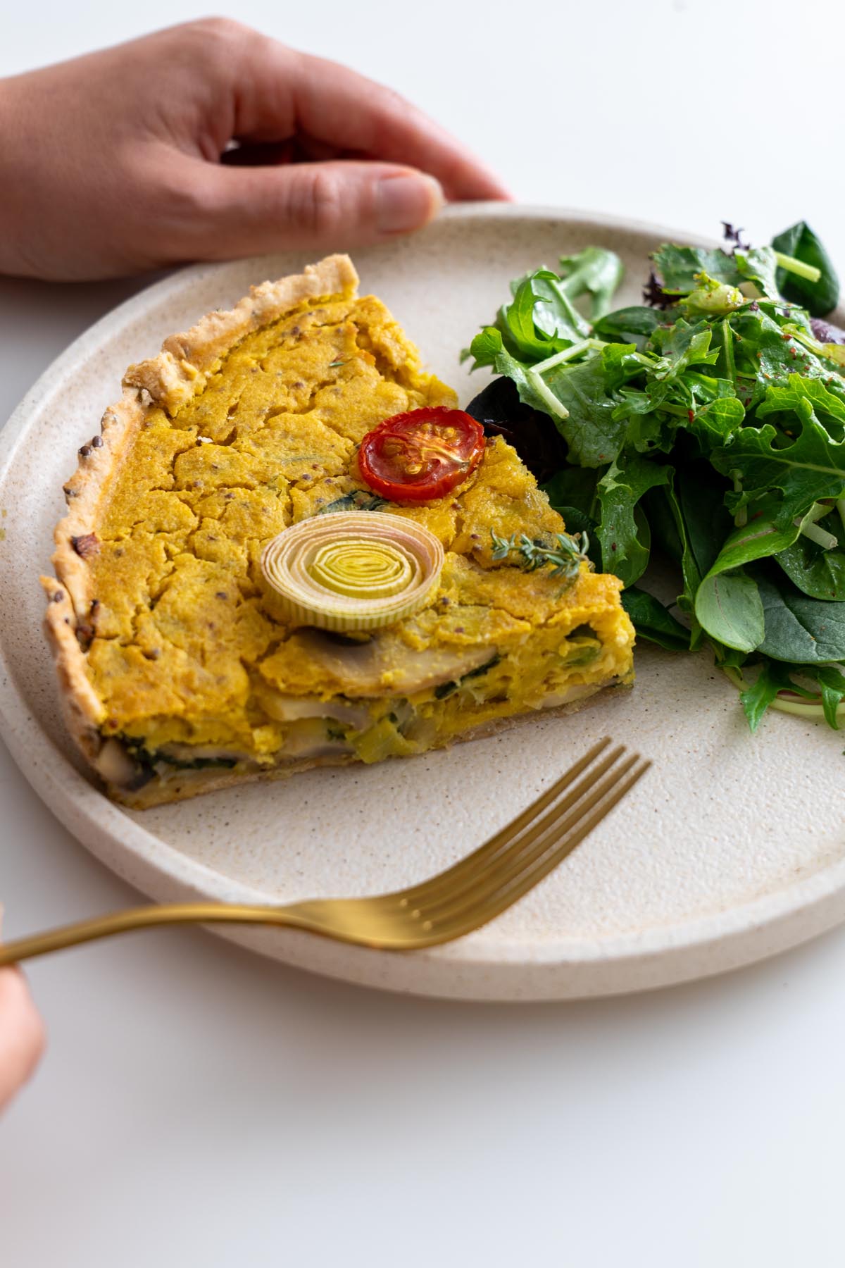 Sliced mushroom and leek quiche on a plate with side salad