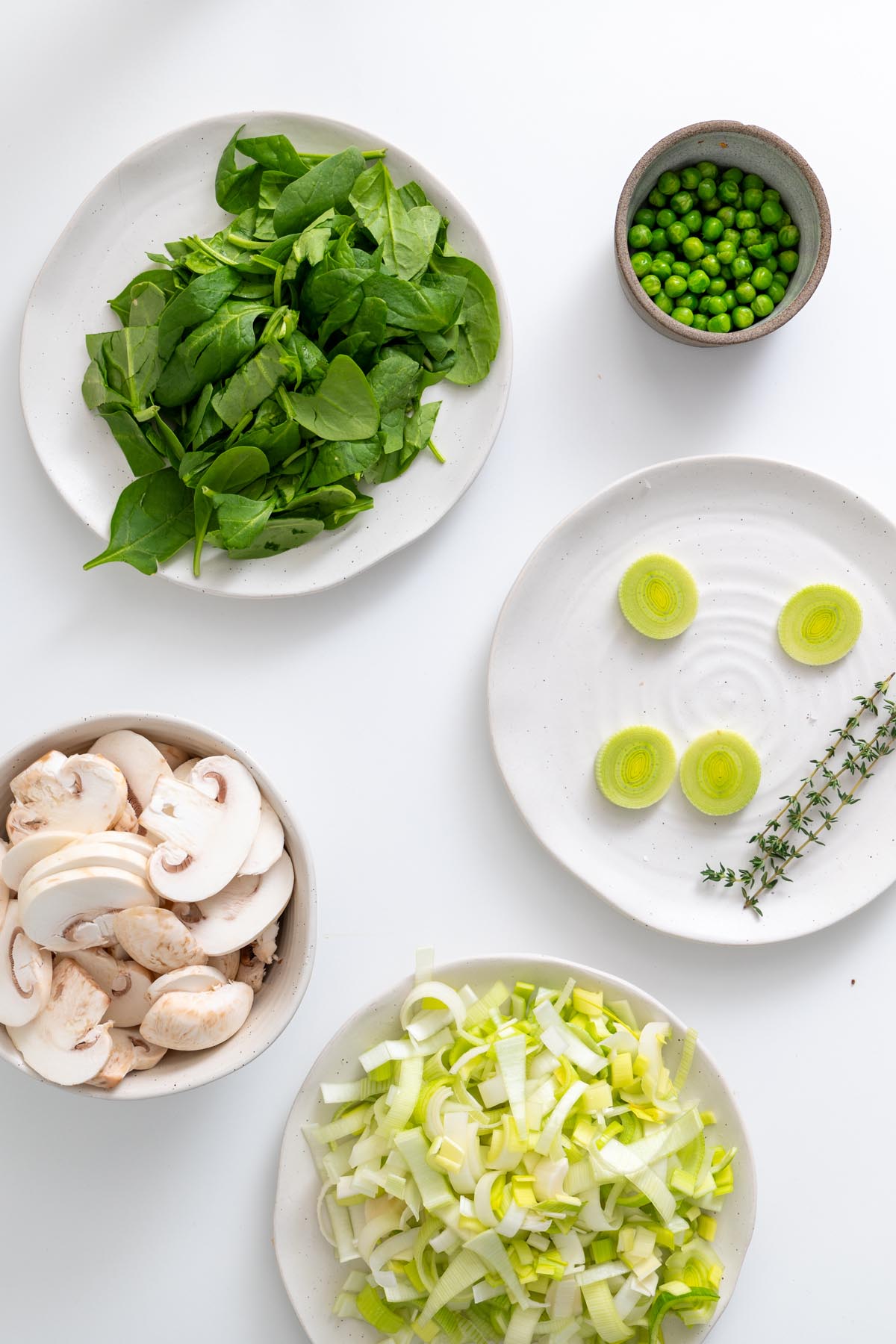 All chopped vegetables laid out on separate plates including leeks, spinach, and mushrooms