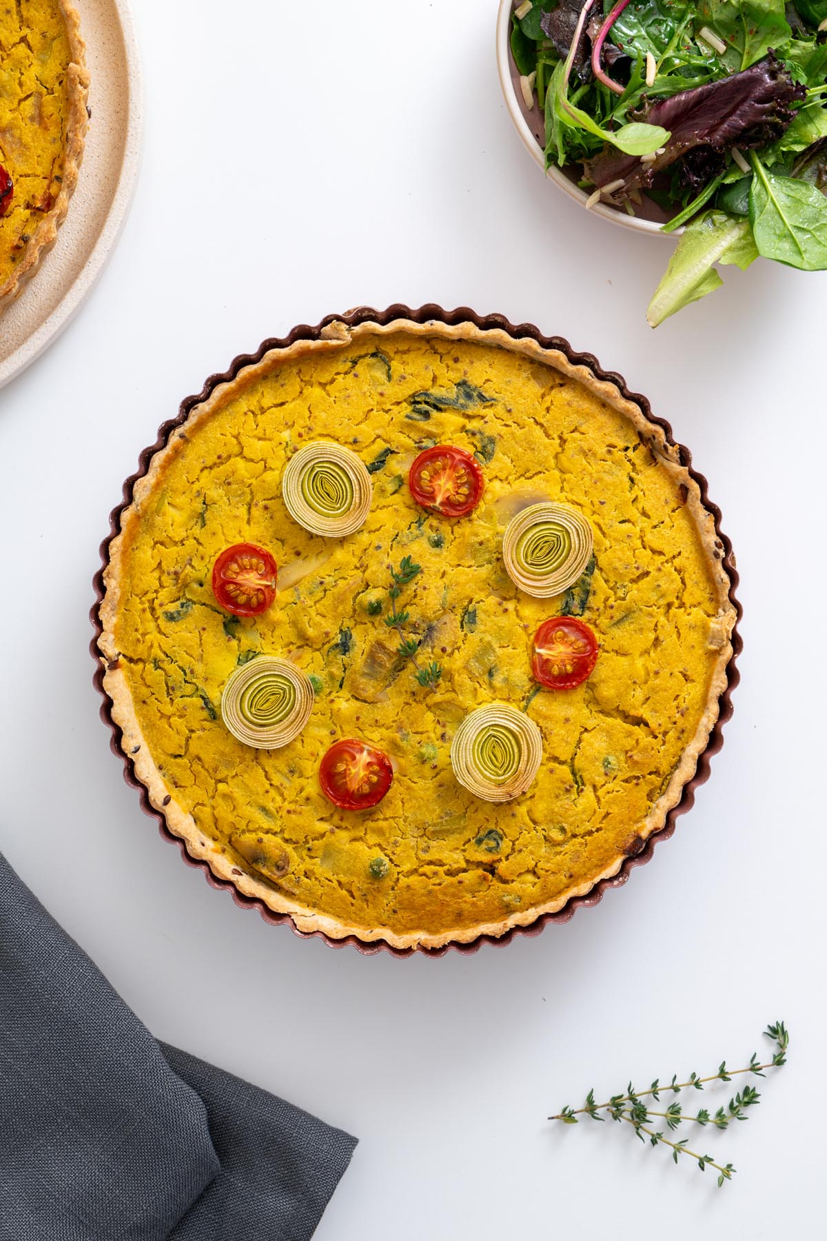 Baked mushroom and leek quiche topped with cherry tomatoes and leek rings