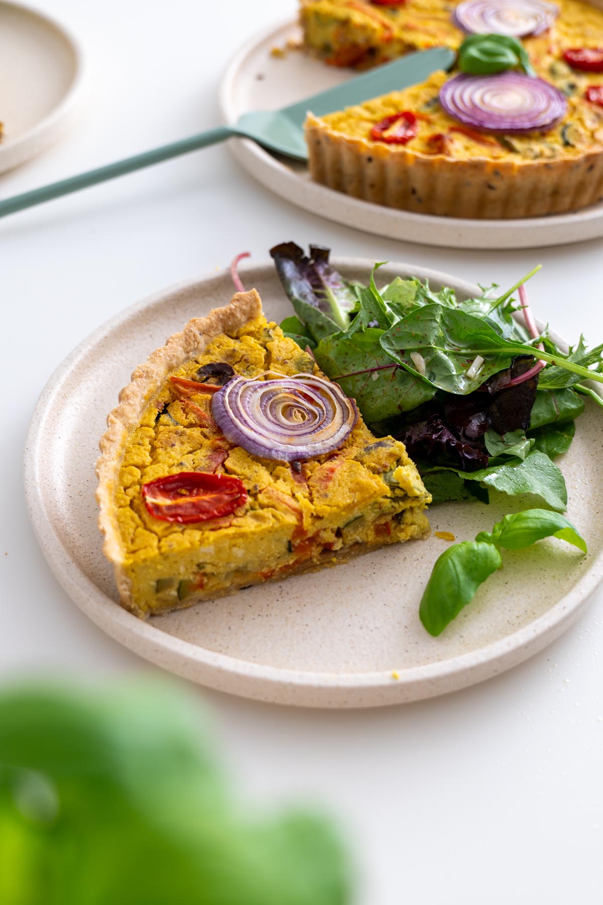 Quiche slice and mixed greens arranged on a round plate