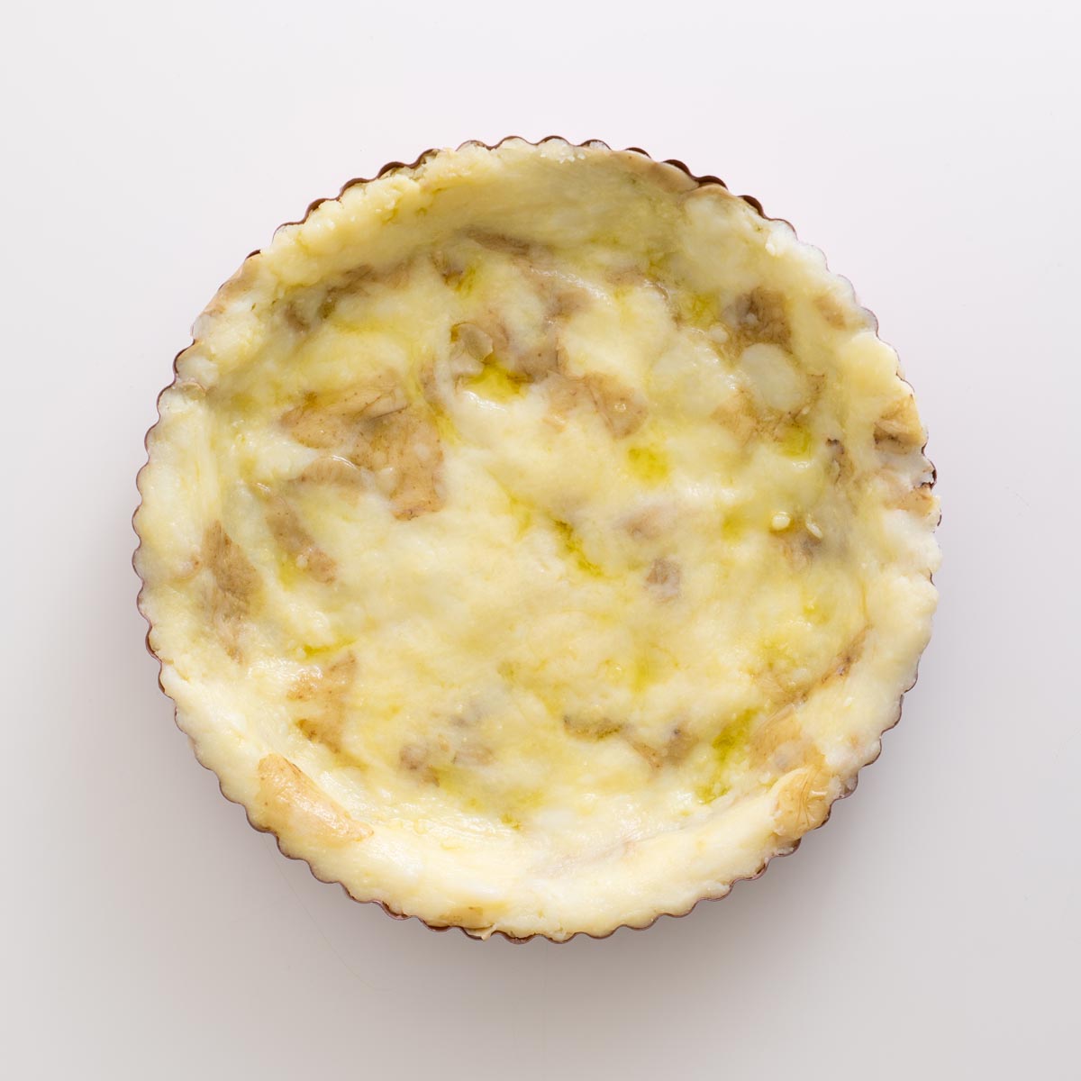 Unbaked mashed potato layer pressed into the tart tin
