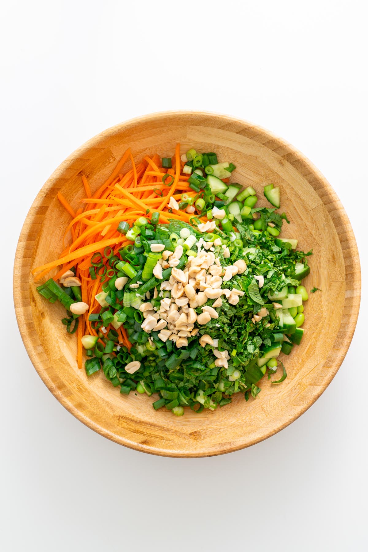 All salad ingredients chopped and ready in a wooden bowl with peanuts on top