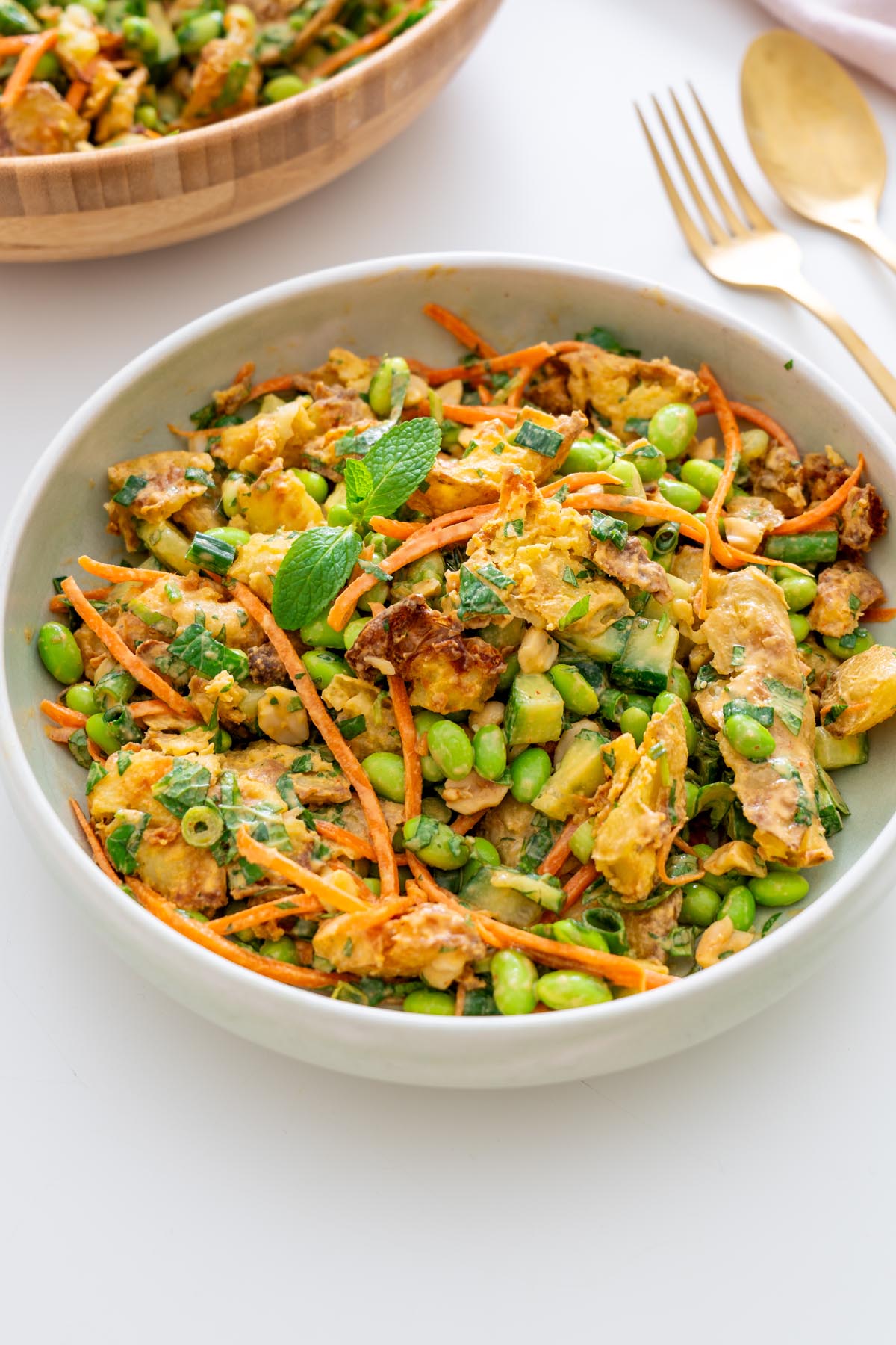 Crispy potato salad served in a white bowl, garnished with mint and ready to enjoy