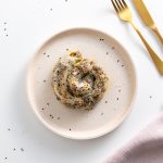 Spiral-shaped rice paper roll spanakopita on a plate, sprinkled with sesame seeds