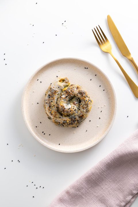 Spiral-shaped rice paper roll spanakopita on a plate, sprinkled with sesame seeds