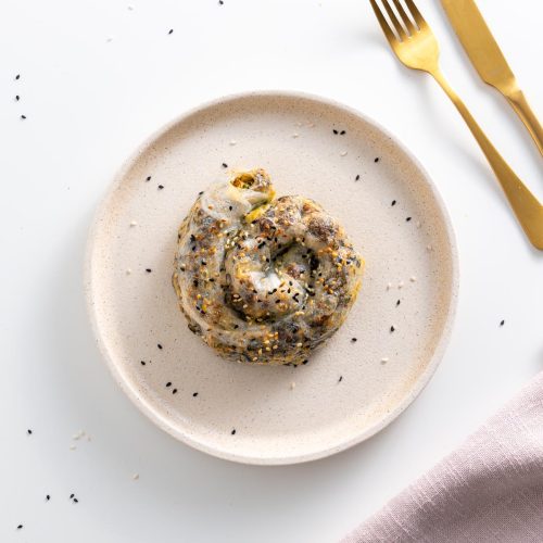 Spiral-shaped rice paper roll spanakopita on a plate, sprinkled with sesame seeds