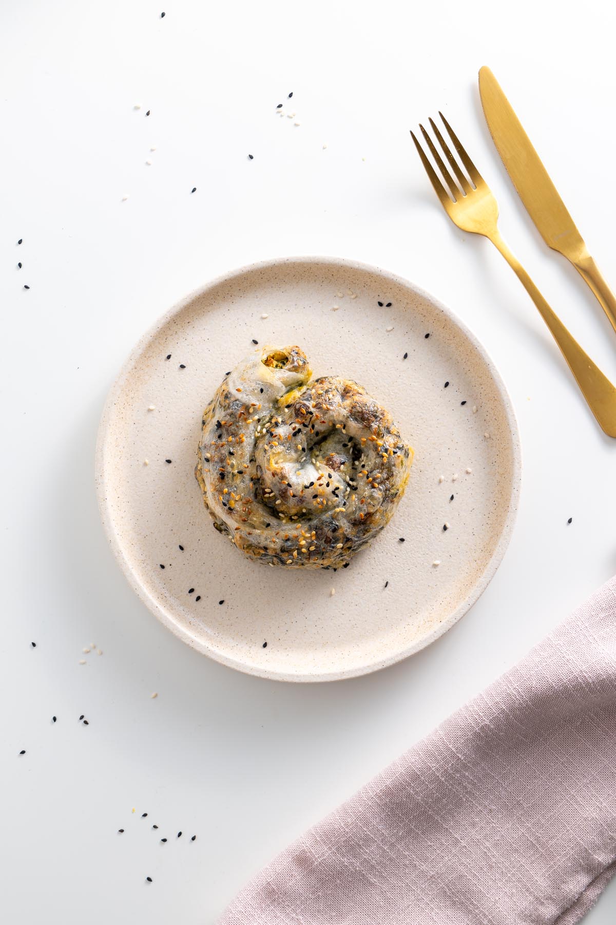 Spiral-shaped rice paper roll spanakopita on a plate, sprinkled with sesame seeds