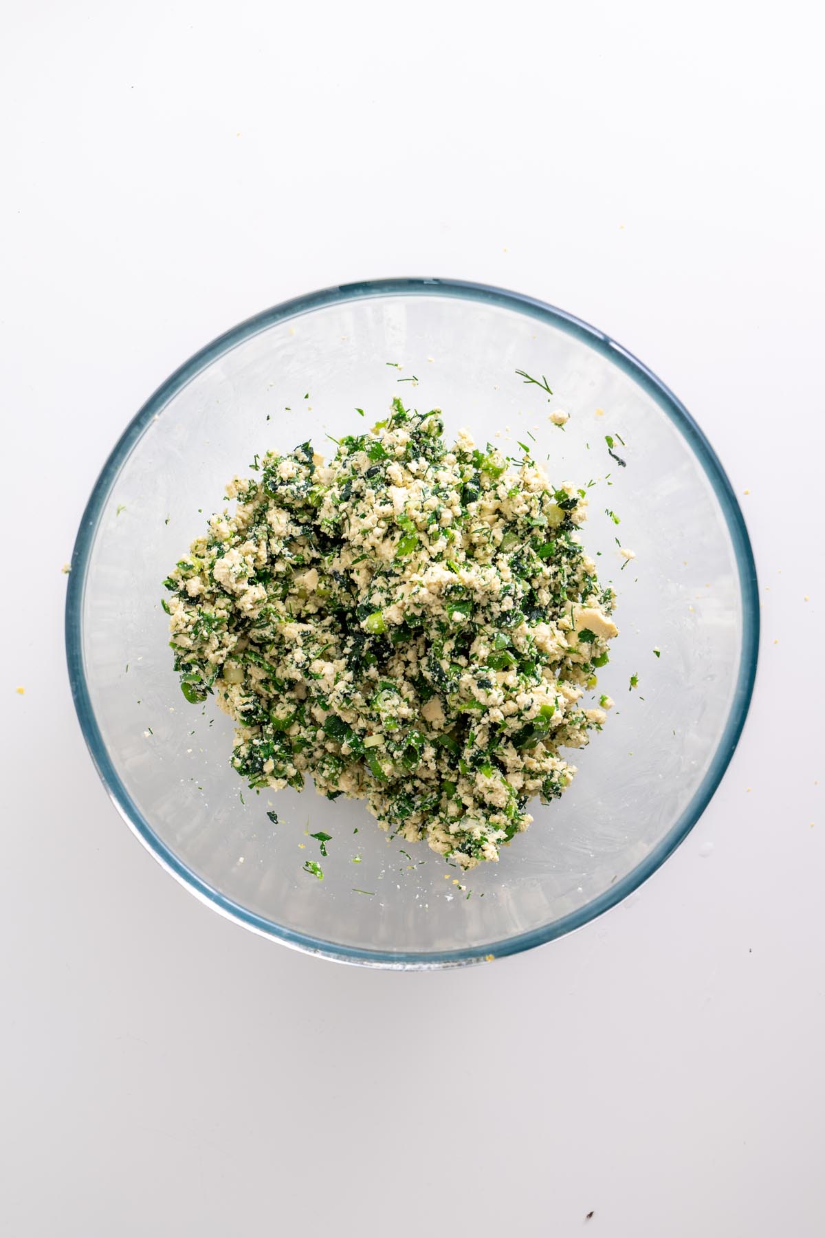 Bowl of tofu, spinach, and herb filling mixture for rice paper roll spanakopita