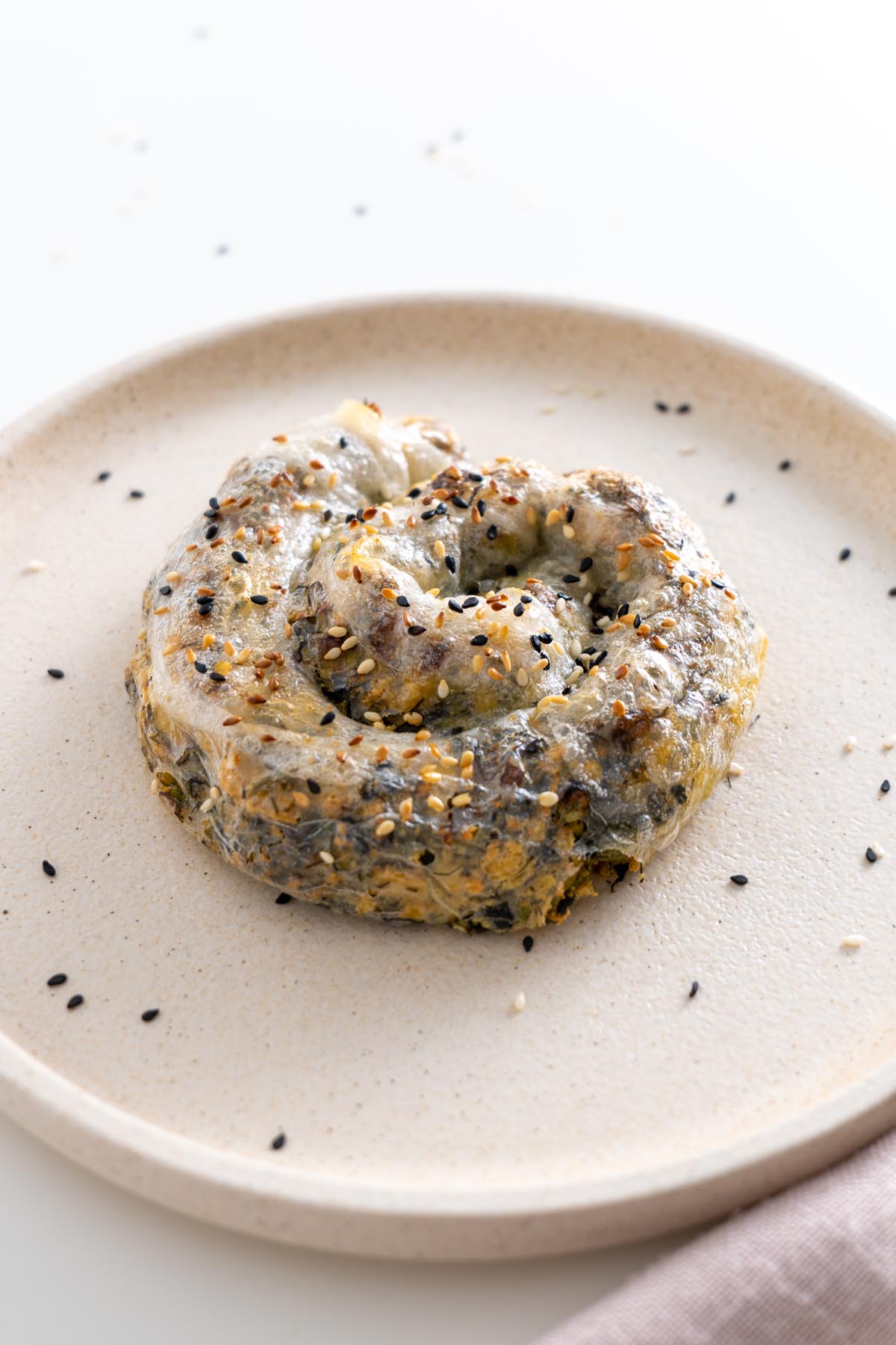 Overhead view of a whole rice paper roll spanakopita on a plate with gold cutlery