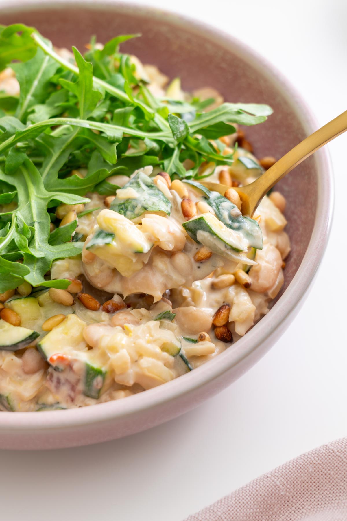 Spoonful of creamy zucchini beans with arugula on top