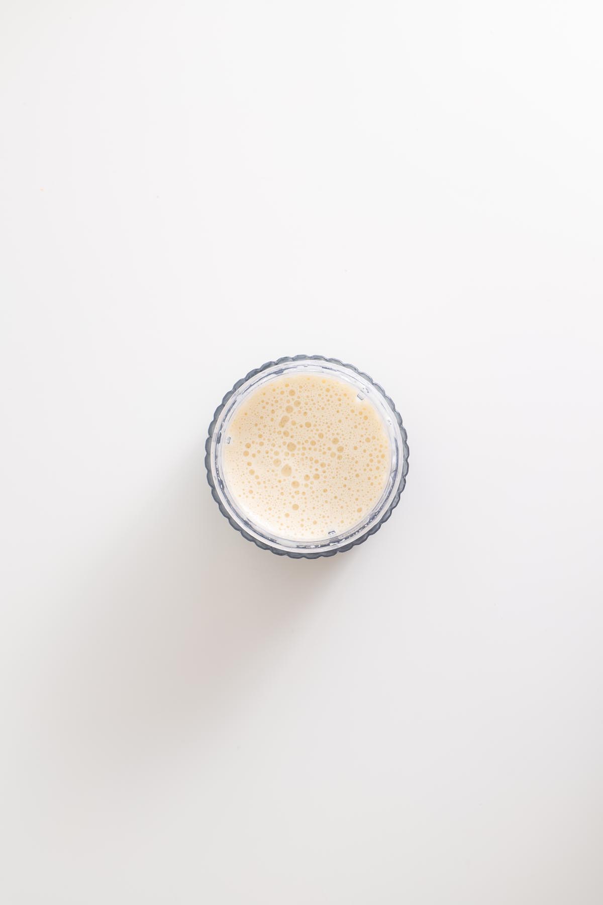 Cashew cream sauce blended in a small bowl on white surface