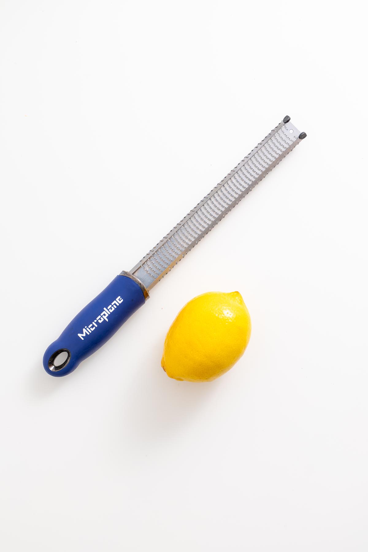 Fresh lemon with a zester on white background