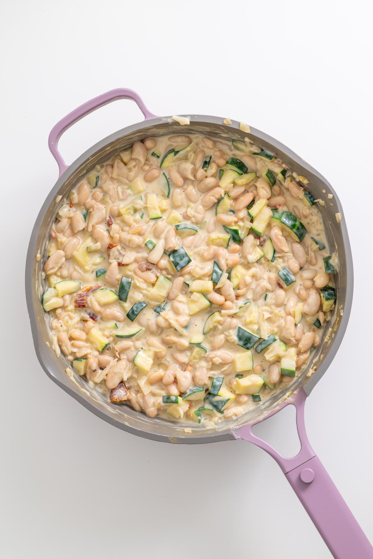 Zucchini and beans cooking in creamy lemon sauce in skillet