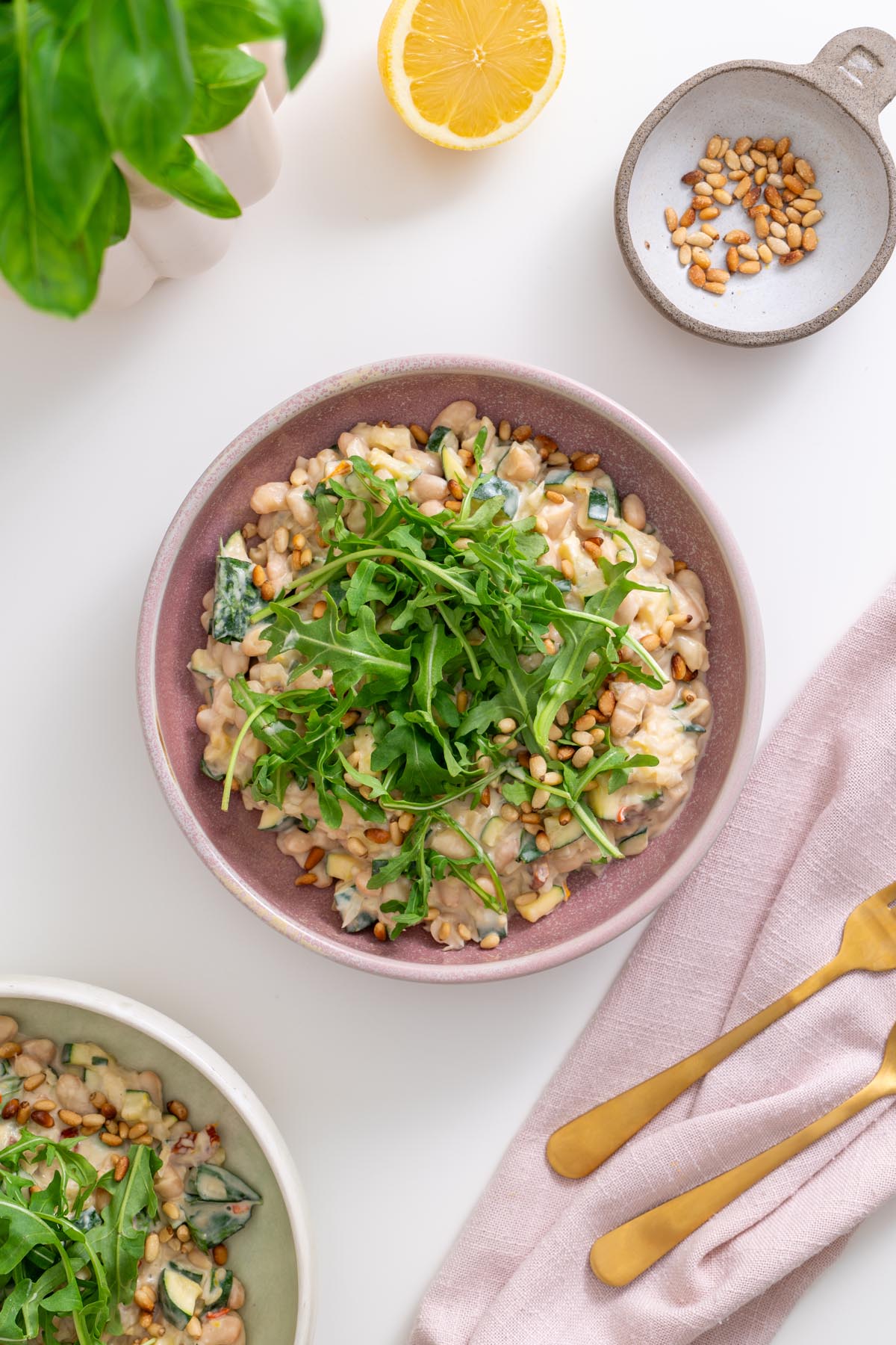 Bowl of creamy lemon zucchini beans topped with arugula and pine nuts