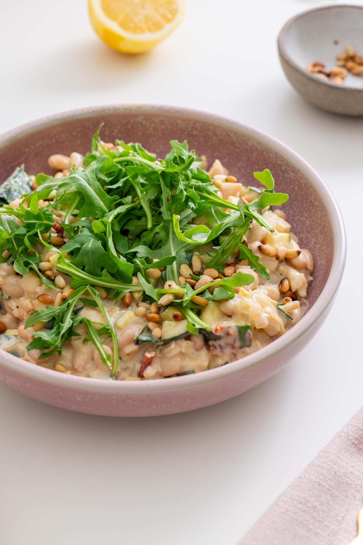Close-up of creamy zucchini beans with arugula and pine nuts
