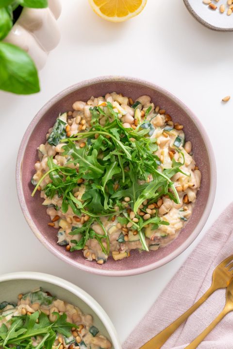 Top view of creamy zucchini and beans with fresh arugula garnish