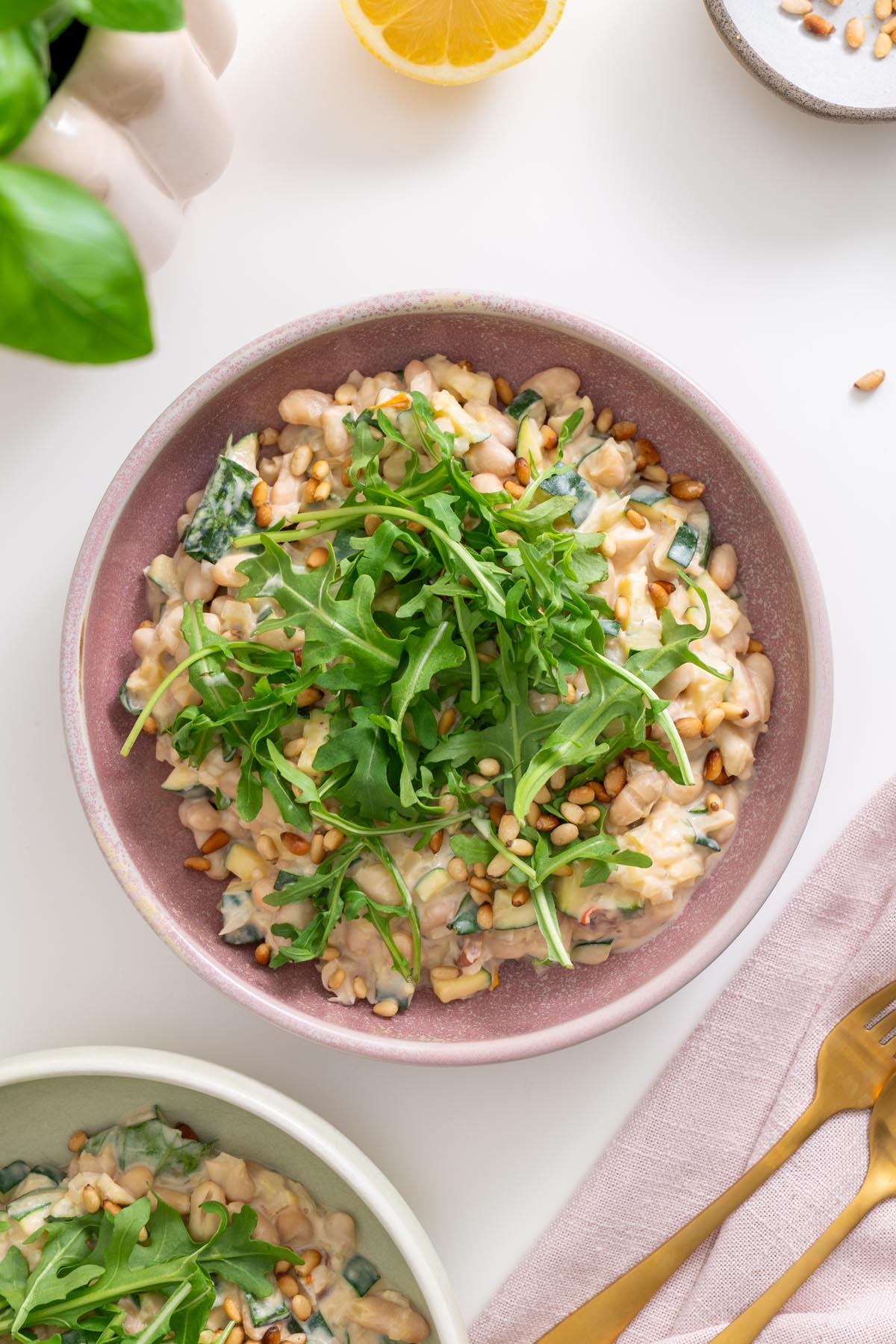 Top view of creamy zucchini and beans with fresh arugula garnish